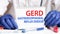Doctor holding a tablet with text: GERD. GERD - GASTROESOPHAGEAL REFLUX DISEASE, medical concept