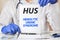 Doctor holding a tablet with text: HUS. HUS - Hemolytic Uremic Syndrome, medical concept