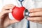 Doctor holding toy heart and stethoscope, closeup