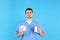Doctor holds menstrual calendar, pads and bottle of pills on blue background