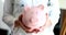 Doctor holds pink piggy bank and medical financial savings in hands