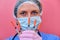 Doctor holds syringes in hands on a red background, concept. Young woman nurse in blue uniform with syringes for injection against