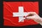 A doctor holds a test tube with a positive blood test for coronavirus in front of the Swiss flag. Covid-19 epidemic, infection,