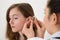 Doctor Inserting Hearing Aid In The Ear Of A Girl