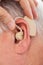 Doctor inserting hearing aid in senior man\'s ear