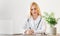 Doctor lady prescribing course of treatment, sitting at workplace