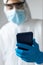 Doctor with latex gloves and coronavirus protective clothing looking at the mobile phone