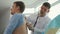 A Doctor Listens to Lungs with a Stethoscope To a Young Man in a Clinic Office.