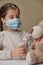 Doctor little girl in mask playing with a toy bear. Child doctor concept. Inhalation