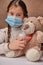 Doctor little girl in mask playing with a toy bear. Child doctor concept. Inhalation