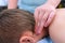 Doctor massagist making therapeutic massage to teen boy on neck in clinic.