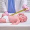 Doctor measures the growth of a newborn baby. A nurse in uniform checks the girth of the child head and abdomen