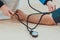 A doctor measuring blood pressure of a male patient with sphygmomanometer and stethoscope