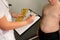 Doctor measuring overweight boy. Friendly nutritionist measures waist.