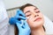 Doctor in medical gloves with syringe injects botulinum under eyes for rejuvenating wrinkle treatment. Filler injection