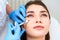 Doctor in medical gloves with syringe injects botulinum under eyes for rejuvenating wrinkle treatment. Filler injection