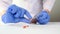 Doctor or nurse in blue latex gloves squeezes tablets, pills out of the blister on white table close up,disease