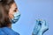 Doctor or nurse with thermometer in hand in mask and medical gloves,  on blue background. Coronavirus COVID-19