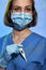 Doctor or nurse with thermometer in hand, wearing in mask and medical gloves,  on studio background. Coronavirus COVID-19