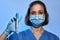 Doctor or nurse with thermometer in hand, wearing in mask and medical gloves,  on studio background. Coronavirus COVID-19