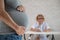 Doctor obstetrician gynecologist at his desk in the background. Close-up of a pregnant woman& x27;s belly.