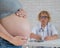 Doctor obstetrician gynecologist at his desk in the background. Close-up of a pregnant woman& x27;s belly.