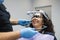 Doctor orthodontist installs a system for diagnosing jaw joints and occlusion for a woman patient. Modern dental equipment.