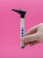 Doctor otolaryngologist holds an otoscope in his hand on a pink background, close-up. Auditory