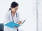 Doctor with paper file. Asian female doctors writing up medical document or patient examination notes by pen on clipboard.