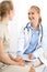 Doctor and patient having a pleasure talk while sitting at the chairs at hospital office. Healthcare and medicine