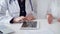 Doctor and patient sitting at the table and talking. The pediatrician in a blue dotted blouse and white medical coat