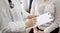 Doctor and patient view. Female physician is filling up a medical records form near a woman having a medical examination