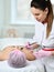 Doctor prepares the patient`s face for a cosmetic procedure by applying a special coating with a brush