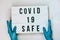 Doctor in protective gloves holding Lightbox with text COVID 19 SAFE. Back to school. Social distancing. School quarantine concept