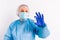 A doctor in protective medical equipment and latex disposable gloves holds an ampoule with a vaccine and shows it to the