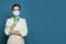 Doctor in protective medical mask and nitrile surgical gloves on blue background, medicine, safety and virus protection concept