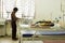 Doctor without protective suit and mask is checking the infected aging child patient in the hospital room, by keeping social