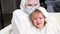 doctor in protective suit, mask, gloves and glasses calms down little sick girl.