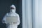 Doctor in protective suit and mask uses laptop