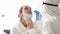 Doctor in protective suit takes swab from a woman nose