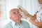 Doctor putting drops into a senior man\'s eyes