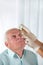 Doctor putting drops into a senior man\'s eyes