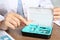 Doctor putting hearing aid into box at table, closeup