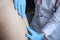 Doctor in rubber gloves palpating pain points near patients spine in clinic closeup