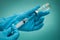 Doctor's hand in medical holds syringe and covid vaccine vial on blue background. Close up, vignetted