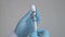 The doctor`s hand wearing blue surgical gloves and injecting the Covid-19 vaccine into the syringe