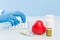 Doctor`s hands in blue medical gloves are typing on a white keyboard, next are pills and a red heart on a blue background. concep