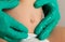 Doctor& x27;s hands in green medical gloves examine an umbilical hernia in a child, close-up.