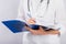 Doctor`s hands in a white coat hold a folder and fill out a medical document close-up isolated on a white background.