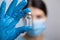 Doctor scientis in protective gloves and mask holding glass vial with injection liquid. Vaccination against influenza and